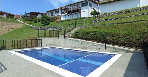 a swimming pool with blue water in front of a house at Espectacular Apto a 5 minutos del parque del café in Montenegro