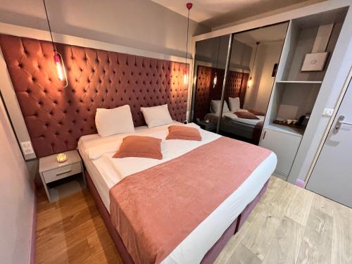 ein Schlafzimmer mit einem großen Bett mit einer roten gepolsterten Wand in der Unterkunft Paris Luxury Guest House - CDG Aéroport in Roissy-en-France