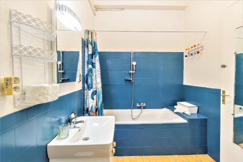 La salle de bains bleue et blanche est pourvue d'un lavabo et d'une baignoire. dans l'établissement L'IMPERIA loft by Booking Guys, à Nice