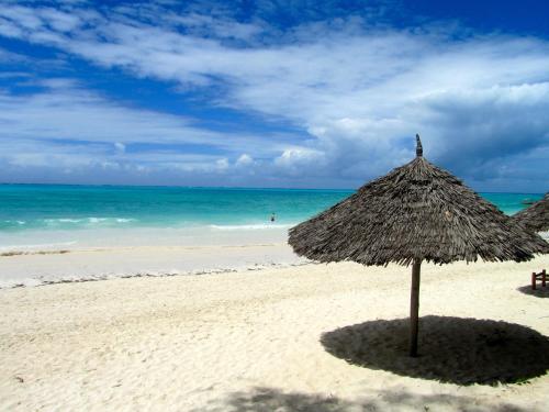 a straw umbrella on a beach with the ocean at Cristal Resort in Paje