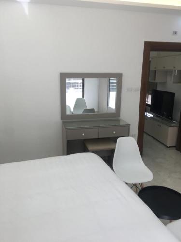 1 dormitorio con cama, escritorio y silla blanca en New and cosy apartment in Amman (Al Weibdeh), en Amán