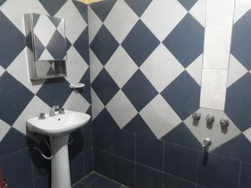 baño con lavabo y azulejos azules y blancos en Casa Huguito en Tinogasta