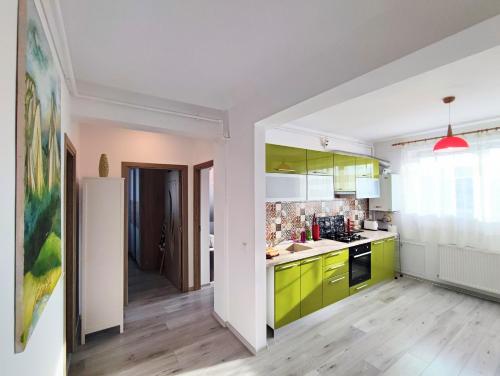 a kitchen with yellow and green cabinets and a hallway at Quiet and Cozy 2 bedroom flat with free parking included in Floreşti