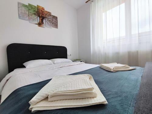 1 dormitorio con 1 cama con 2 toallas en Quiet and Cozy 2 bedroom flat with free parking included en Floreşti