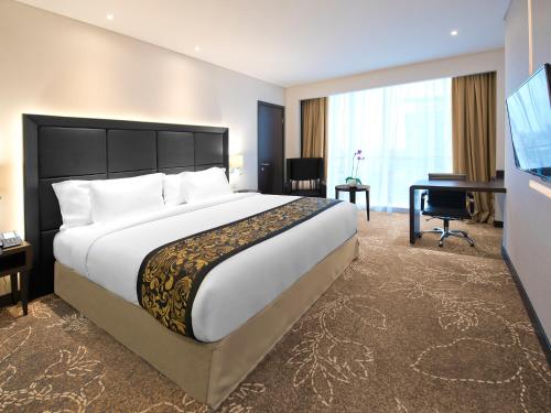 a hotel room with a large bed and a flat screen tv at Melia Makassar in Makassar