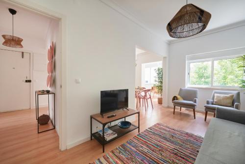 a living room with a couch and a tv at Sunset Balcony Apartment, By TimeCooler in Lisbon