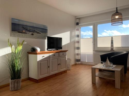 - un salon avec une télévision, un canapé et une table dans l'établissement Kleine Brise Apartment 5, à Büsum