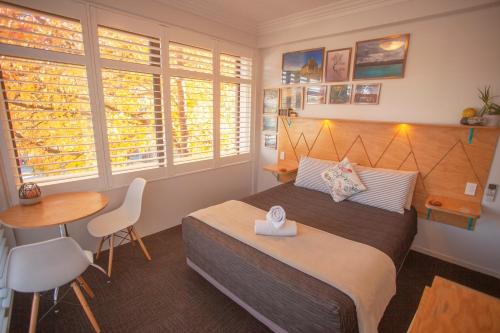a hotel room with a bed, table, chairs and a window at Absoloot Hostel Queenstown in Queenstown