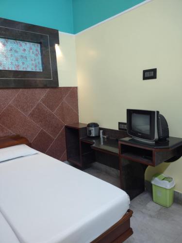 a hotel room with a bed and a tv at Krishna Lodge in Tiruchchirāppalli