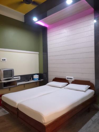 a bedroom with a large bed with a pink lighting at Krishna Lodge in Tiruchchirāppalli