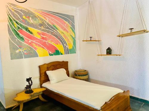 1 dormitorio con 1 cama y una pintura en la pared en Hotel Mimosa Airport, en Toubab Dialaw