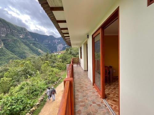 two children walking on a porch of a house with mountains in the background at La Rivera de Gocta in Cocachimba