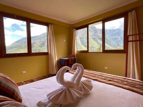 two swans sitting on a bed in a room with windows at La Rivera de Gocta in Cocachimba