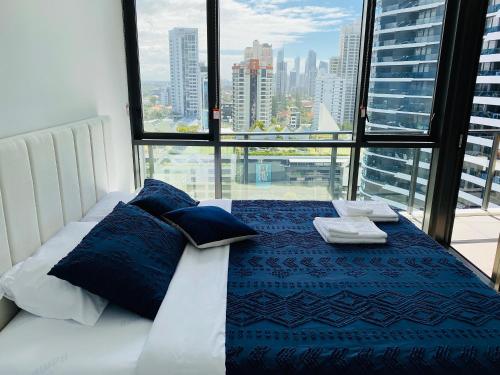 a bed with blue pillows in a room with a window at Koko luxury apartment in Broadbeach in Gold Coast
