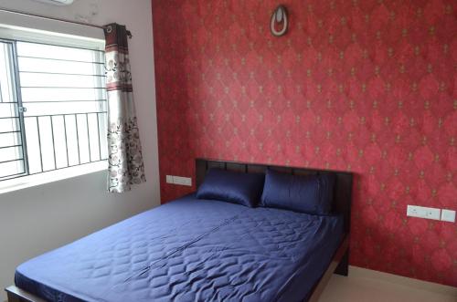 a bedroom with a bed and a red wall at Oviyam Sea view Apartment, feel like home in Chennai