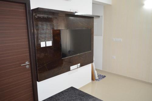 a flat screen tv in a room with a door at Oviyam Sea view Apartment, feel like home in Chennai