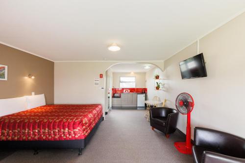 a hotel room with a bed and a kitchen at Manfeild Park Motel in Feilding