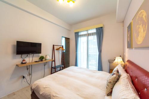 a bedroom with a bed and a flat screen tv at Jinguann B&B in Hualien City