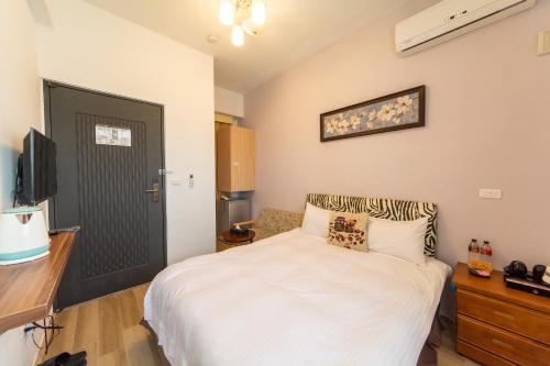 a bedroom with a white bed and a black door at Jinguann B&B in Hualien City
