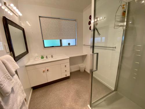a bathroom with a shower and a sink and a mirror at Rathlin Cottage in Twizel