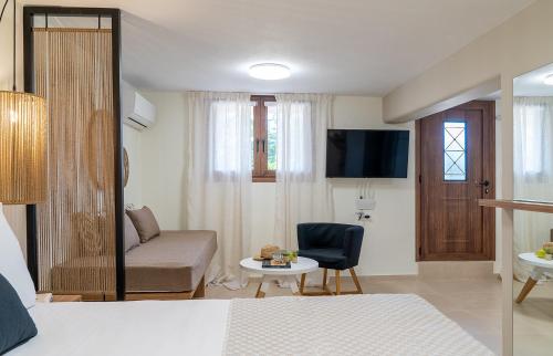 Habitación con cama, sofá y TV. en Olea Suites en Gouves