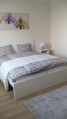 a bedroom with a white bed with a flower on it at River Side Apartman in Kalocsa