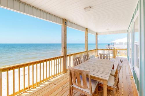 a wooden deck with a table and chairs on the beach at On Deck in Dauphin Island