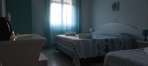 a small bedroom with two beds and a window at Hotel VILLA ITALIA B&B in Porto Azzurro