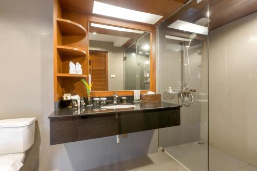 a bathroom with a sink and a mirror and a toilet at Best Western Premier Bangtao Beach Resort & Spa in Bang Tao Beach