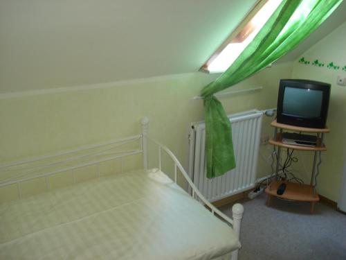 a small bedroom with a bed and a television at Traditionsgasthof Zum Luedertal in Bimbach