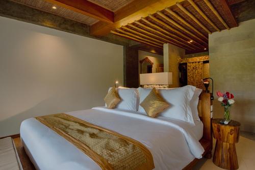 a bedroom with a large bed with white sheets and pillows at Kastara Resort in Ubud