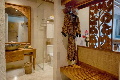 two pictures of a bathroom with a sink and a mirror at Kastara Resort in Ubud