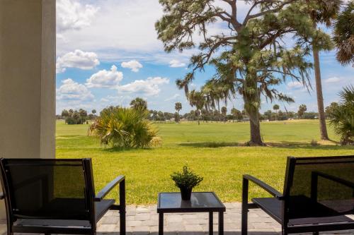 a patio with two chairs and a table and a field at Highest 5 Star Rated Luxury Home 5 Minutes from the Beach! in Melbourne