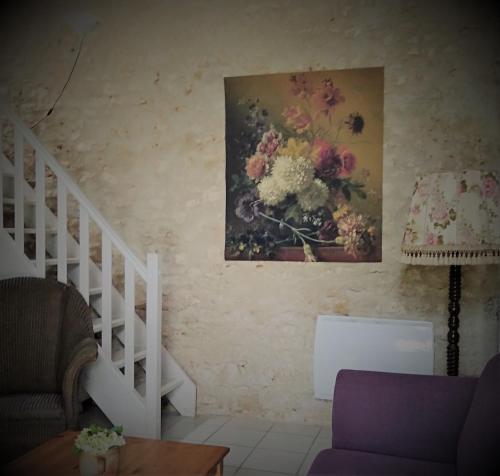 a living room with a painting of flowers on the wall at Gites les Lignons in Champniers