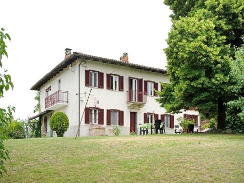 duży biały dom z czerwonymi oknami i drzewem w obiekcie Casa vacanze a Moncucco Torinese w mieście Moncucco Torinese
