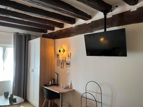 a living room with a desk and a tv on the wall at Hôtel Le Blason in Amboise