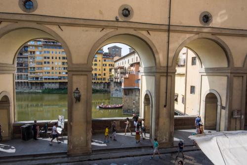 a group of people walking around a building next to a river at Vasari Suite Florence next to Pontevecchio in Florence