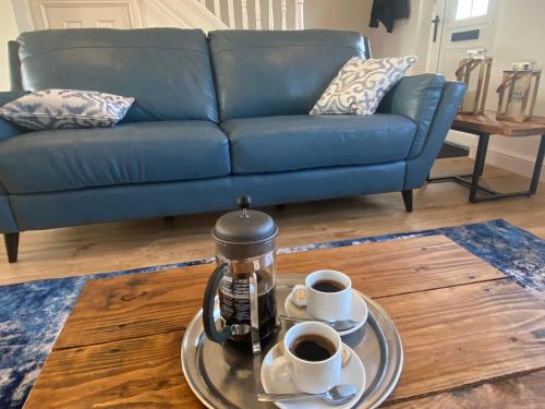 two cups of coffee on a table with a blue couch at Beachcomber in Garlieston