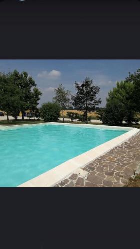 a blue swimming pool with trees in the background at La Locanda degli Artisti in Medelana