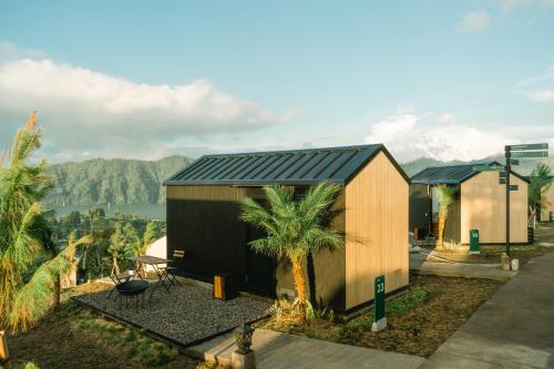 une petite maison avec un toit noir et des palmiers dans l'établissement Bobocabin Kintamani, Bali, à Kintamani