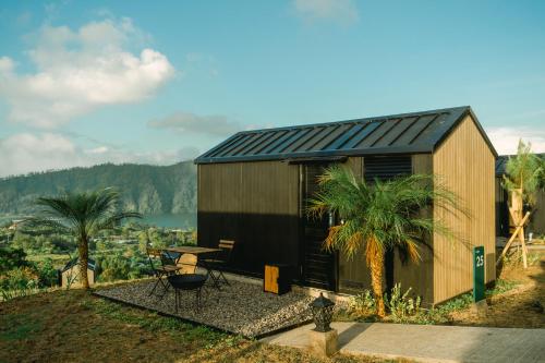 une petite cabine avec une table et des palmiers dans l'établissement Bobocabin Kintamani, Bali, à Kintamani