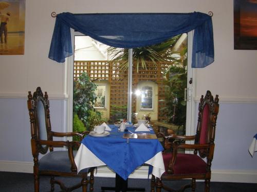 a table with a blue table cloth and two chairs at Kingswinford Guest House in Paignton