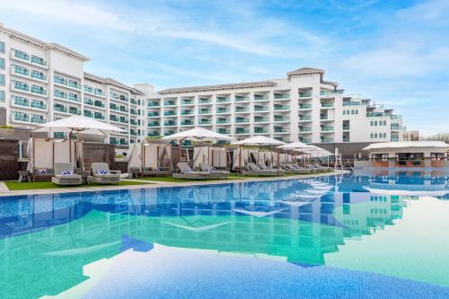 a hotel with a swimming pool in front of a building at Taj Exotica Resort & Spa, The Palm, Dubai in Dubai
