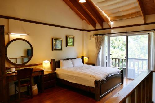 a bedroom with a bed and a desk and a mirror at Ailiga Travel Villa in Renai