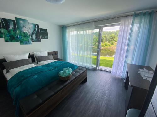 a bedroom with a large bed and a large window at Apartments Saaldorf-Ferienhaus mit 6 Apartments 45qm-120qm direkt am Thüringer Meer-Bleilochtalsperre in Bad Lobenstein