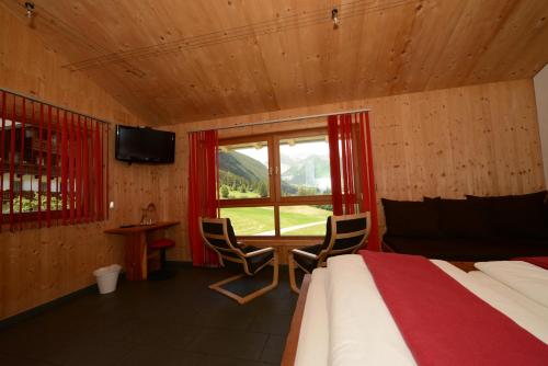 a bedroom with a bed and a window with a table and chairs at Braugasthof Glocknerblick in Kals am Großglockner