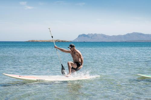 a man standing on a paddle board in the water at Mossa Well Being Hotel - Heated pool in Kato Daratso