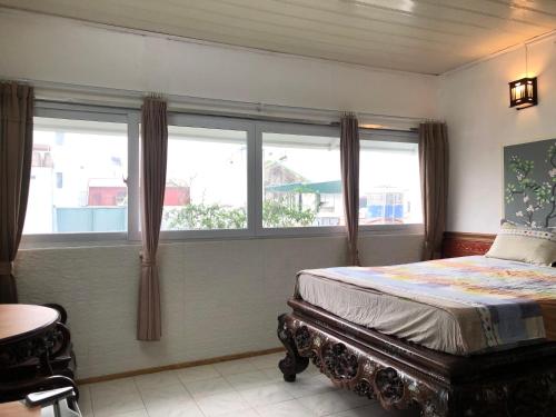 a bedroom with a bed and two windows at North Hostel N.2 in Hanoi