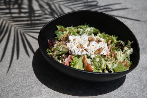 a salad in a black bowl on a table at Mossa Well Being Hotel - Heated pool in Kato Daratso