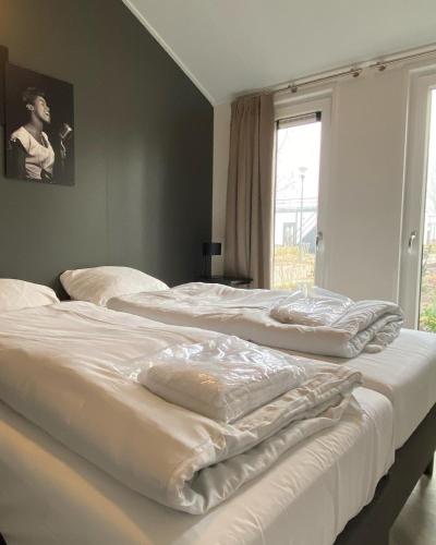 two white beds in a bedroom with a window at Luxe en gezellig chalet aan Veluwemeer 4 pers in Hulshorst